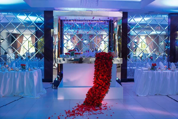Mesa festiva, arco, soportes decorados con composición de flores rojas y vegetación, velas y espejos en la sala de banquetes. Mesa recién casados en el área de banquete en la fiesta de boda . — Foto de Stock
