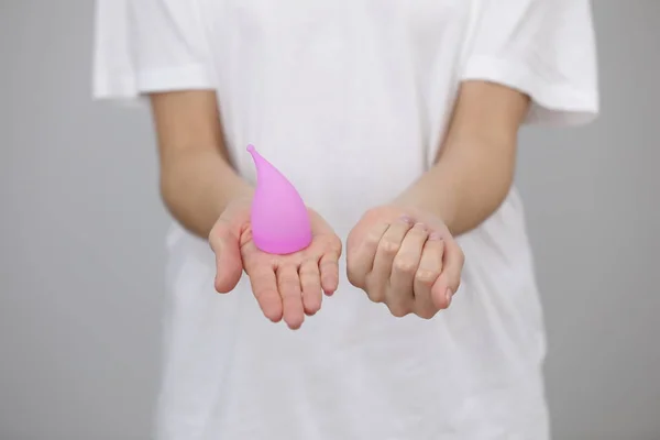 Молодая женщина держит в руках различные виды женской гигиены - менструальная чашка и тампон хранится в ее руке — стоковое фото