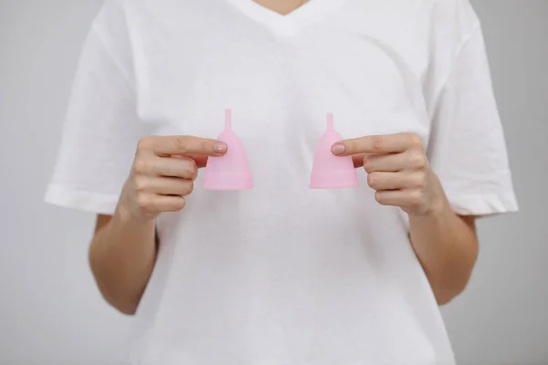 Primer plano de la mano de la mujer sosteniendo copas menstruales de diferentes tamaños. Concepto de salud de las mujeres, cero residuos alternativos —  Fotos de Stock