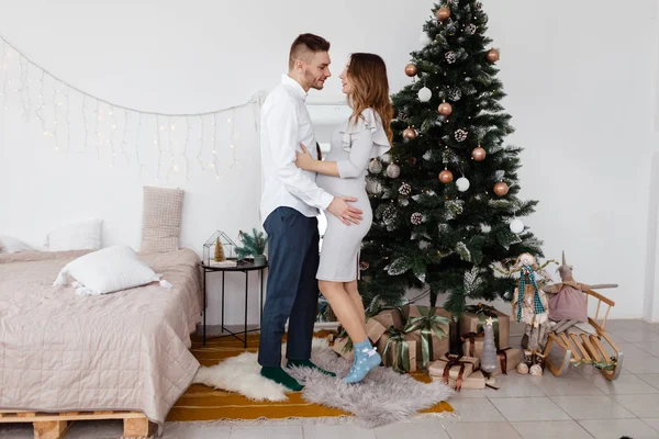 Belo par grávida elegante no amor em um Natal, tendo um resto em férias de Natal antes do Ano Novo. Grande barriga grávida . — Fotografia de Stock