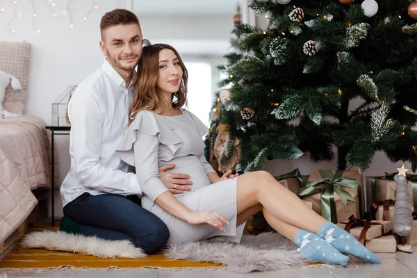 Belo par grávida elegante no amor em um Natal, tendo um resto em férias de Natal antes do Ano Novo. Grande barriga grávida . — Fotografia de Stock