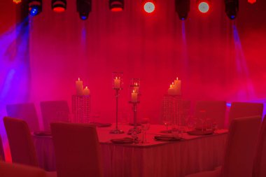 Dekorlu lüks düğün masası, gümüş şamdanlar, mumlar ve mavi ışıkta çiçekler. Seçici fotoğraf