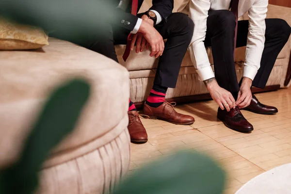 Männerfüße in schicken Schuhen und hellen Socken. Eleganter Mann kleidet Schuhe. Zwei Männerhände binden Schnürsenkel. Männermode. Hochzeitsmode. — Stockfoto