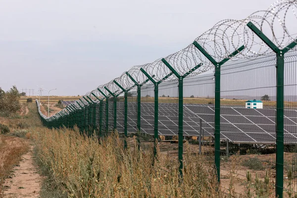 Сонячна електростанція захищена від дороги колючим дротом. Огорожа чутливих ділянок з колючим дротом . — стокове фото