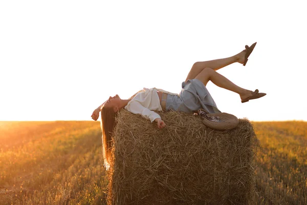 Porträt eines schönen Mädchens auf Heuhaufen auf einem abgeernteten Weizenfeld im Sommer. Selektiver Fokus. — Stockfoto