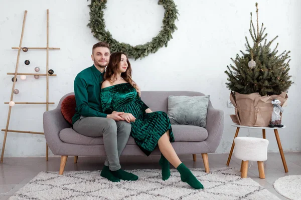 Aimer couple heureux à la maison. famille, Noël, vacances, l'amour et les gens concept heureux jeune couple enceinte assis câlins sur le canapé à la maison près de l'arbre de Noël. focus sélectif . — Photo