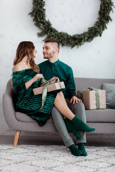 Karácsonyi ajándék. A szerelmesek boldog karácsonyt ünnepelnek. Szerető pár ölelés mosolyogva, miközben kicsomagolja ajándék karácsonyfa hátterét.Micsoda meglepetés. — Stock Fotó