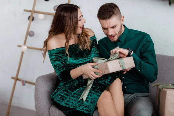 Opening christmas present. Couple in love happy enjoy christmas holiday celebration. Loving couple cuddle smiling while unpacking gift christmas tree background.What a surprise. — ストック写真