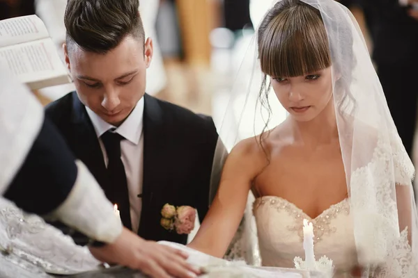 Brautpaar glücklich bei der Trauung in der Kirche. segnet der Priester die heilige Ikone für ein langes Leben für Braut und Bräutigam. Selektiver Fokus. — Stockfoto