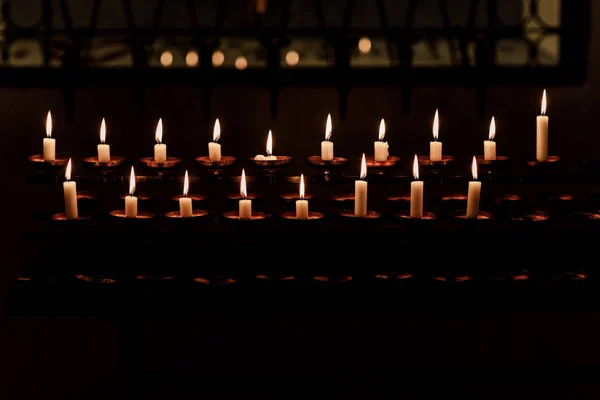 Hořící svíčky v kostele na tmavém pozadí — Stock fotografie