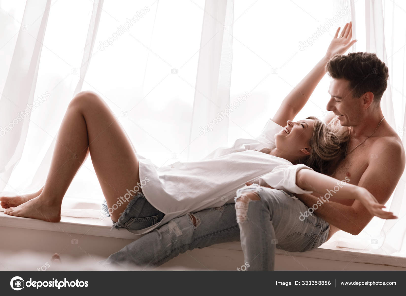 夫妻俩在家里玩得很开心，爱玩的妻子咬着笑的丈夫的耳朵，骑着背，男人和女人在床上玩着孩子气，享受着有趣的亲密时光——