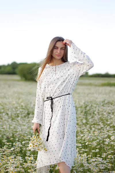 Hermosa joven mujer disfrutando de un campo de margaritas, hermosa chica relajándose al aire libre, divirtiéndose, sosteniendo ramo de margaritas, feliz joven dama y naturaleza verde primavera, concepto de armonía . — Foto de Stock