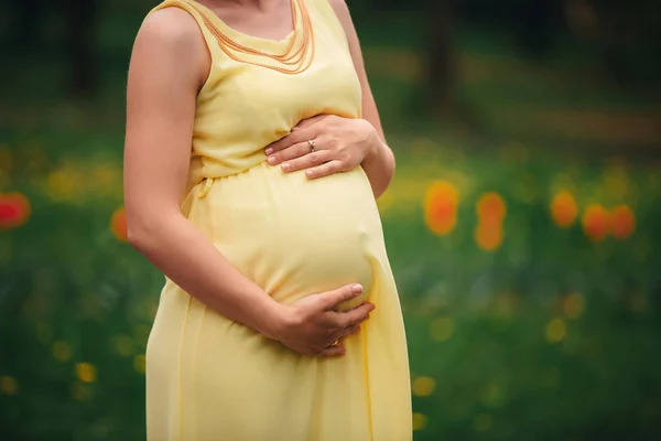 Fata gravidă într-o rochie galbenă îmbrățișându-și stomacul în câmp — Fotografie, imagine de stoc