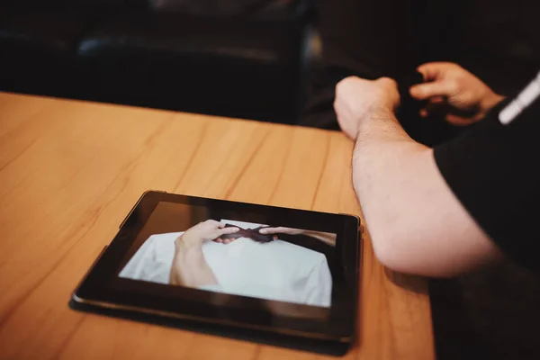 Uomo che guarda video su tablet come legare una cravatta. sposi preparazione del mattino . — Foto Stock