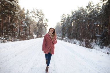 Young pretty stylish woman having fun in the winter snowy forest in motion.