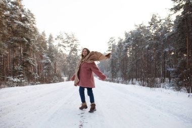 Young pretty stylish woman having fun in the winter snowy forest in motion.