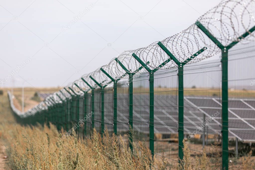 Solar power station protected from road by barbed wire fence. Fencing of sensitive sites with barbed wire.