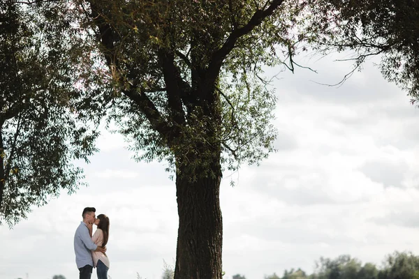 Jong romantisch koppel heeft plezier in de zomer zonnige dag in de buurt van het meer. Genieten van samen op vakantie. Man en vrouw knuffelen en kussen. — Stockfoto