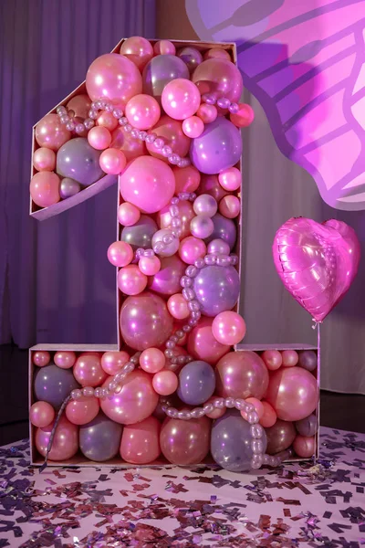 Big number one of the pink color baloons for children's birthday. A light, pink and purple interior decorated for the girl's first birthday. Birthday party. — Stockfoto