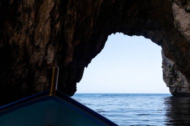 View from a small motor boat on a natural stone arch near the coast of Malta.