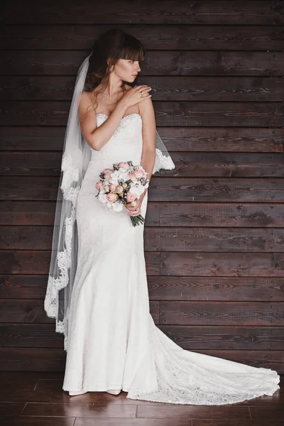 Retrato de uma bela noiva jovem e elegante. Maquiagem e penteado na mulher. Vestido de noiva branco elegante e buquê de rosas brancas e rosa na mão. manhã da noiva . — Fotografia de Stock