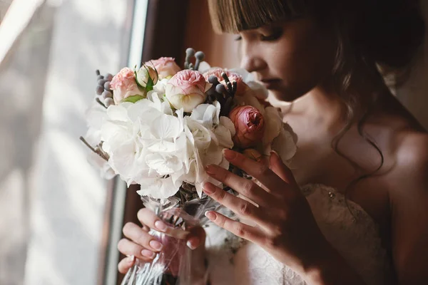 バラの花束とアジサイ室内で美しい花嫁の肖像画。窓の近くの豪華なドレスでかなり幸せな花嫁。結婚式の朝の準備 — ストック写真