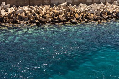 sea background and pebbles. Sea pebbles on the beach. Sea pebbles on the beach sand with transparent water. Natural sea stones closeup. Beach smooth pebbles. Tourism and travel themed.