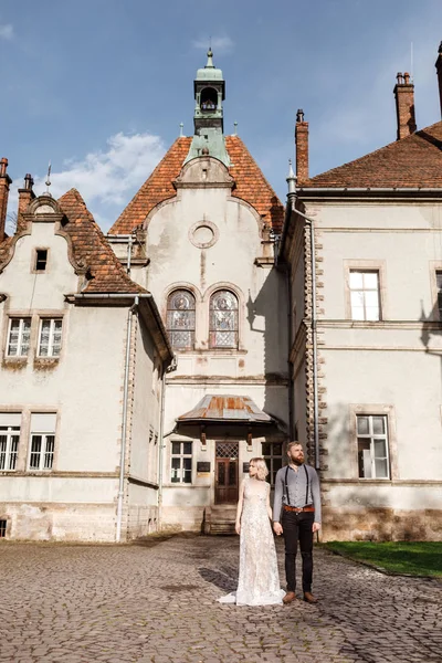 Beautiful wedding couple are walking near old castle, ancient restored architecture, old building, old house outside, vintage palace outdoor. Romantic love in vintage atmosphere street