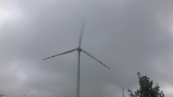 Wind power turbin on cloudy sky background. Windmill turbine generating clean renewable energy in agricultural field landscape. Wind energy station. Ecology and nature conservation — Stock Video