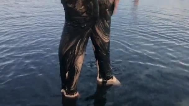 Mujer joven haciendo cuerpo Máscara de piel sana con barro médico negro en el lago de agua salada . — Vídeos de Stock