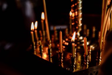 Geceleri kilisede birçok mum yanıyor. Karanlıkta mum yakan bir grup. Yakın plan. Boşluğu kopyala.