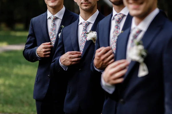 Eleganti uomini dello sposo con cravatta fiori macchiati. fiori bianchi in asola, gli uomini dello sposo sono vestiti con un vestito scuro. Il giorno del matrimonio. Outfit del giorno . — Foto Stock