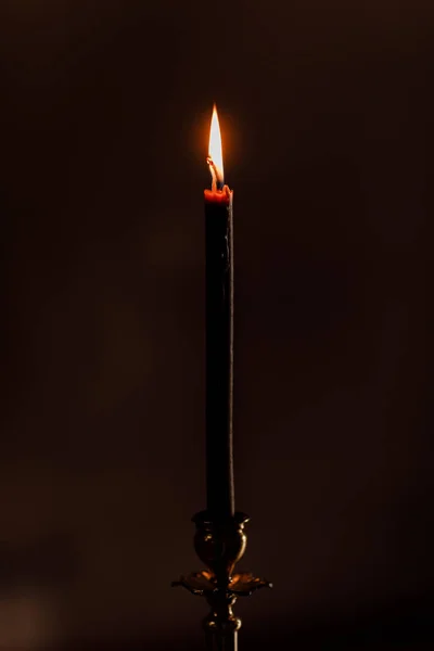 Una vela encendida por la noche sobre el fondo negro de la iglesia. Vela aislada en fondo negro. Primer plano. enfoque selectivo — Foto de Stock