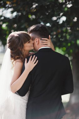 Harika genç gelin ve şık damat düğün günü açık havada sarılıyorlar. Düğün çifti, lüks düğün..