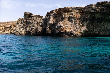 Denizde kayalar. Deniz kıyısının arka planındaki dağ yamaçları. Dağ manzaralı deniz manzarası. Bir deniz manzarasının fotoğrafı..