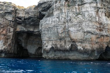 Denizde kayalar. Deniz kıyısının arka planındaki dağ yamaçları. Dağ manzaralı deniz manzarası. Bir deniz manzarasının fotoğrafı..