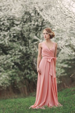 Kadınlar günü. Bahar parkındaki çiçek açan ağacın yanında uzun boylu, şık bir kadın. Pembe elbiseli sarışın kız. Çiçek açan ağaçlar