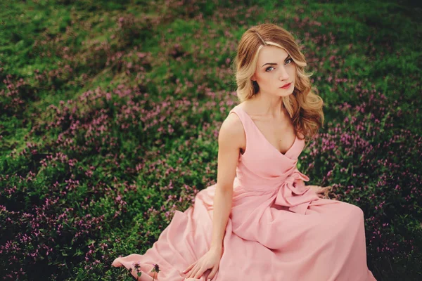 美丽的金发姑娘 开着五颜六色的花 在开着花的春天公园里 穿着粉红衣服 有着化妆和发型的女孩 浪漫女人的艺术作品 看着相机的漂亮柔情模型 — 图库照片