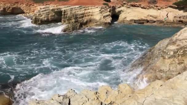 Deniz dalgaları kayalara çarpıyor. Kristal berrak deniz manzarası, katmanlı kayalar ve güzel doğa. Gök mavisi deniz kıyısı. seçici odak — Stok video
