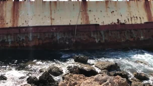 De zeegolven slaan tegen het verlaten koopvaardijschip op Cyprus. Uitzicht op de kristalheldere zee, gelaagde rotsen en prachtige natuur en schip. Azure kust. selectieve focus — Stockvideo