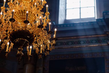 Katedral Hıristiyan kilisesinde büyük bronz avize ve elektrikli mumlar. Kilisenin penceresinden gün ışığı. seçici odak.