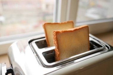 Mutfakta ekmek dilimleri olan bir tost makinesi. Pencerede geleneksel kahvaltı. seçici odak.