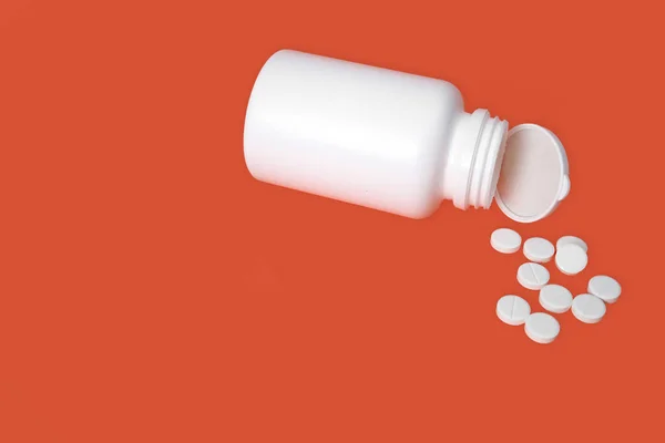 白色药丸分散在红色背景的白色罐子里 有选择的重点 健康的概念 — 图库照片