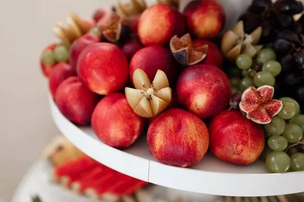 different kinds of fresh fruit on a tray on a banquet. fruit background with peaches, grapes and figs. selective focus.