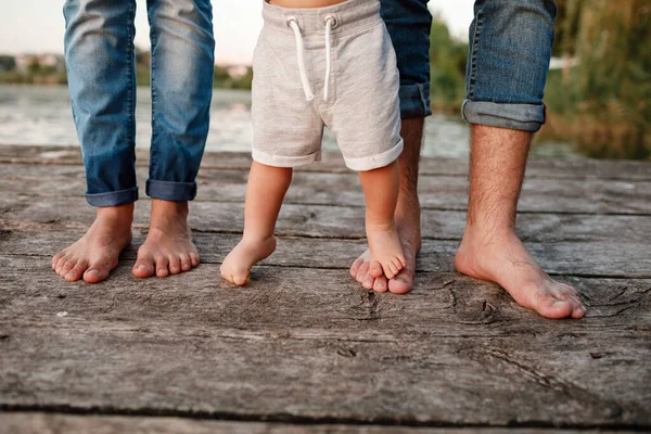 Bare feet of family. Wooden bridge. Mom, dad and baby walk bare feet on the wooden bridge. Happy young family spending time together. The concept of family holiday. copy space.
