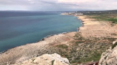 Deniz kıyısı manzarası, güneşli bir günde mavi deniz suyuyla kıyıda kayalar.
