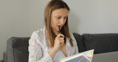 Evde dizüstü bilgisayarla çalışan iş kadını. Serbest çalışan biri kanepedeki deftere bir plan yazsın. Grafikleri analiz eden profesyonel bir kadın. Karantinadaki iş yerinin sahibi. Evde kal.