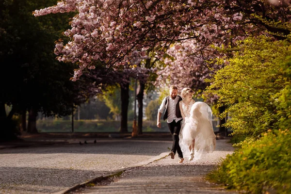 Weseli Nowożeńcy Biegający Mieście Szczęśliwi Pośród Kwitnących Drzew Nowożeńcy Bawią — Zdjęcie stockowe