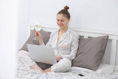 Kendini tecrit eden bir kadın. Evde yatarken dijital tablet kullanan ve internetten yemek sipariş eden ya da film izleyen genç mutlu kadının portresi.