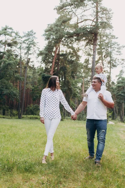 Babacığın parkta, ormanda omzunda bir kız çocuğu taşıyor. Yaz tatili kavramı. Babalar günü, anneler günü, bebekler günü. Birlikte vakit geçirmek. Aile görünüşü. seçici odak.